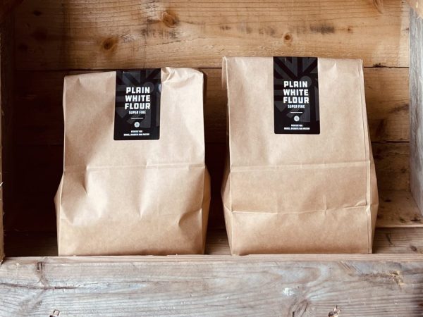 Two bags of Norfolk & Better Plain White Flour, super fine, on a rustic wooden shelf
